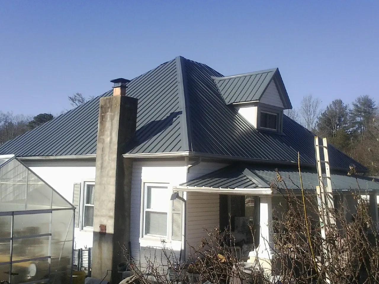 Dark blue standing seam metal roof on a white farmhouse with dormer — Slate & Tile Roof Repair by Roofing Brothers in Bamberg