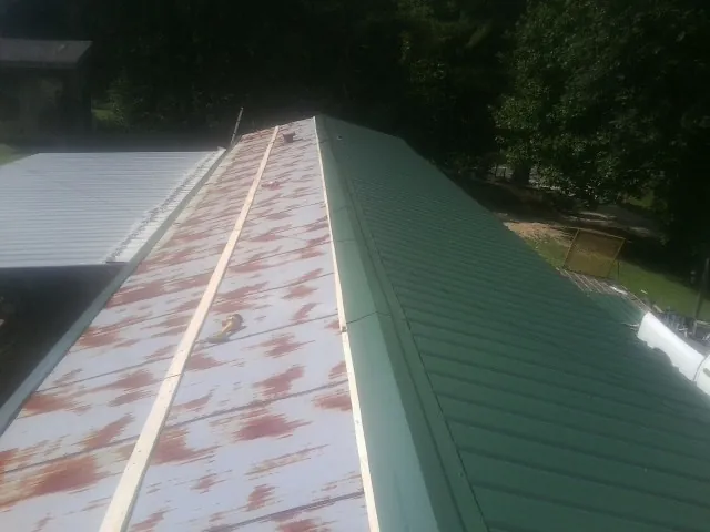 Old rusted panels beside newly installed green metal roofing — Wind Damage Roof Repair by Roofing Brothers in Bamberg