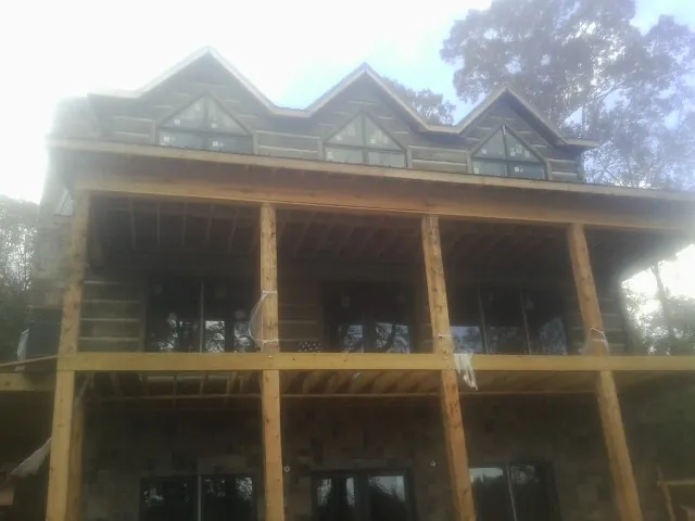 Dormers and porch framing on a large log home under construction — Roof Coating work by our crew in Bamberg