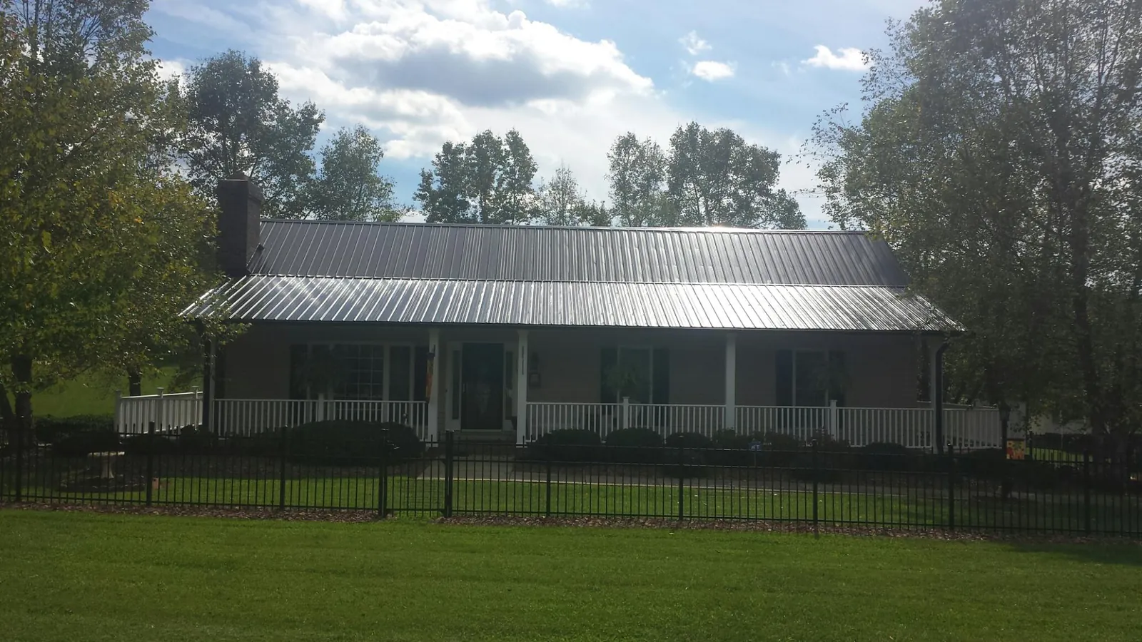 Gray metal roof on a brick ranch with a full width front porch — Gutter Guard Installation work by our crew in Bamberg