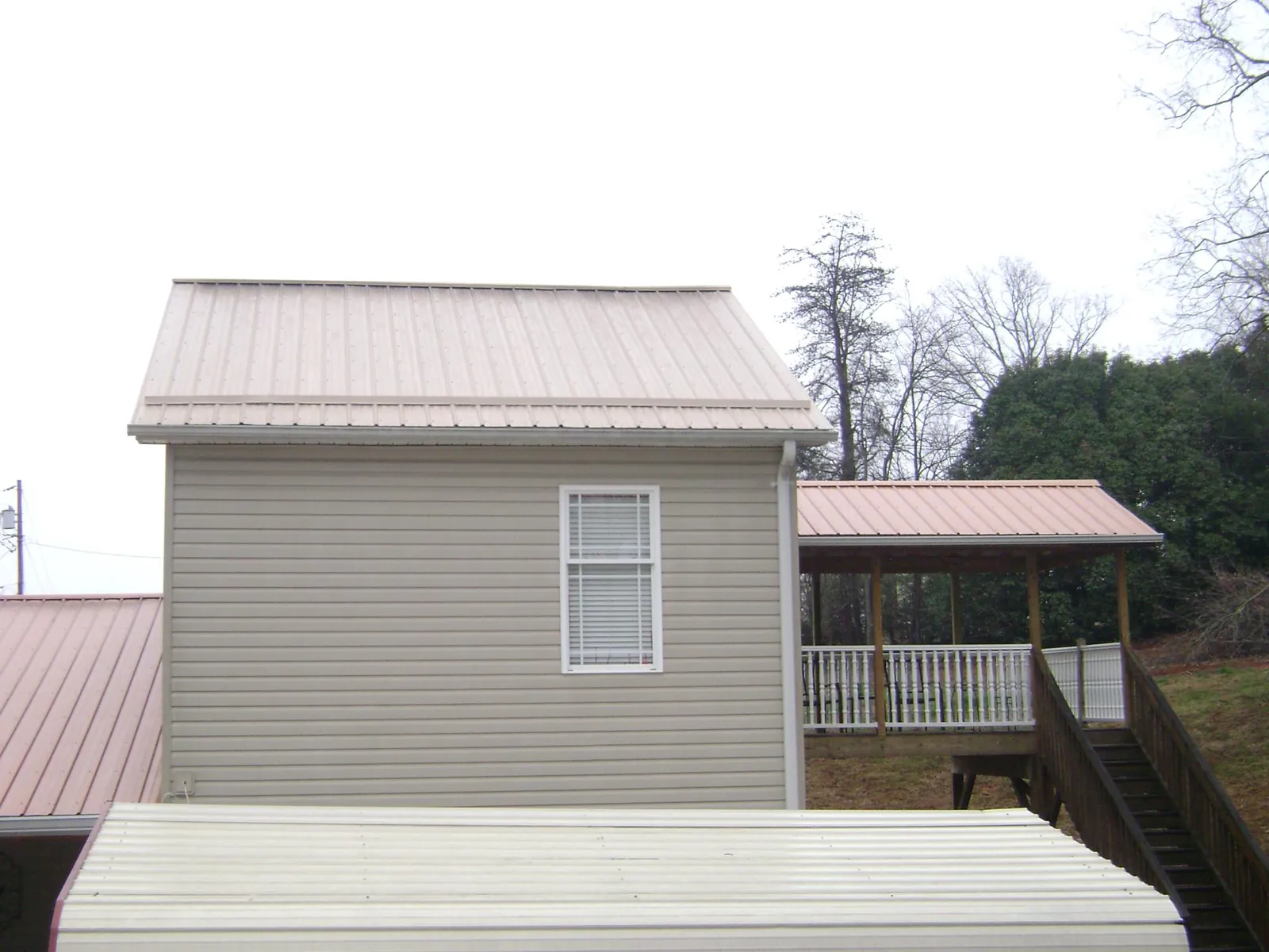 Tan metal roofs on a two story addition and attached porch, from a Roof Replacement job in Bamberg