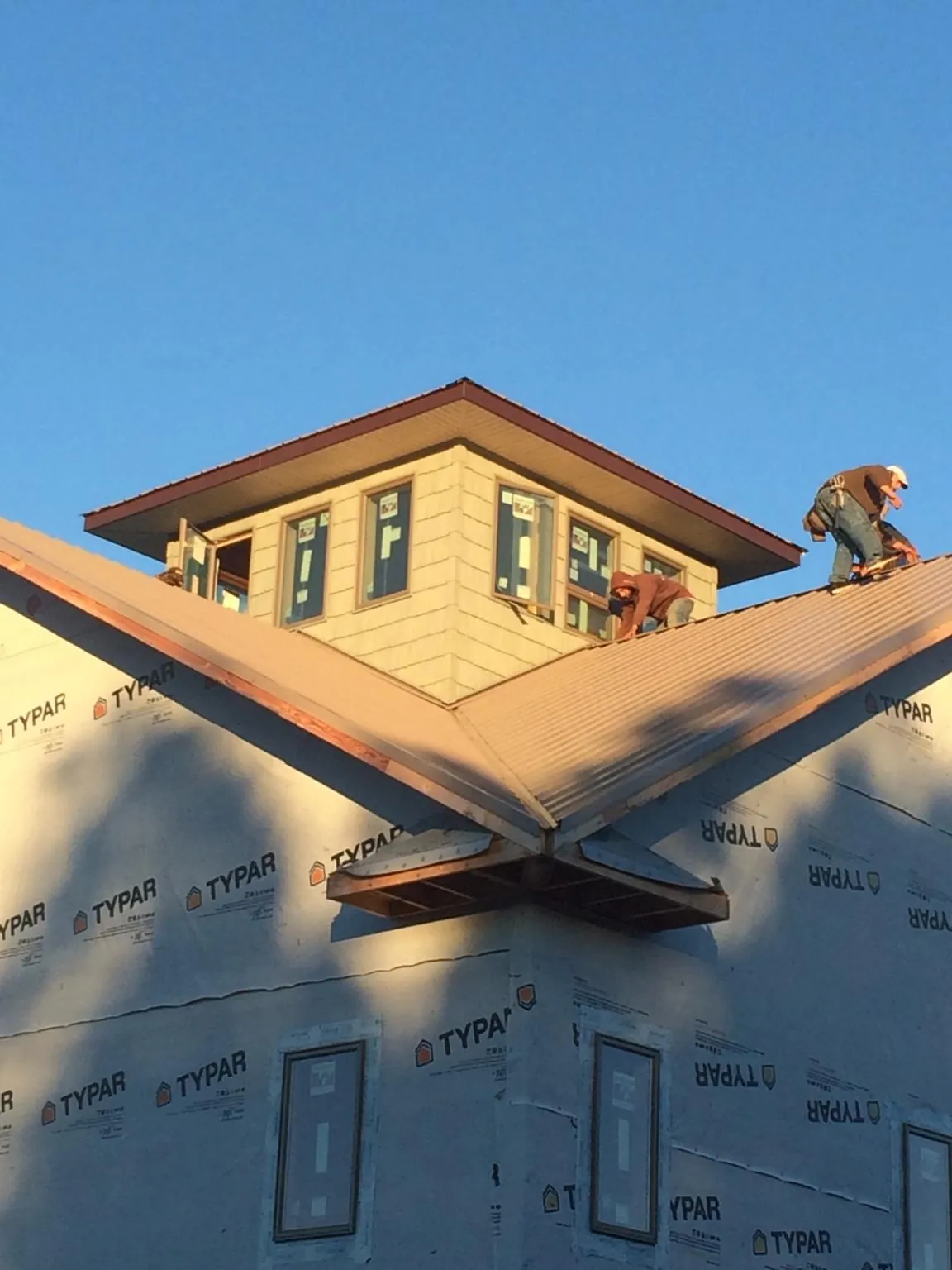 Roofers working around a rooftop cupola on a new metal roof at sunset — Roof Waterproofing in Bamberg by Roofing Brothers